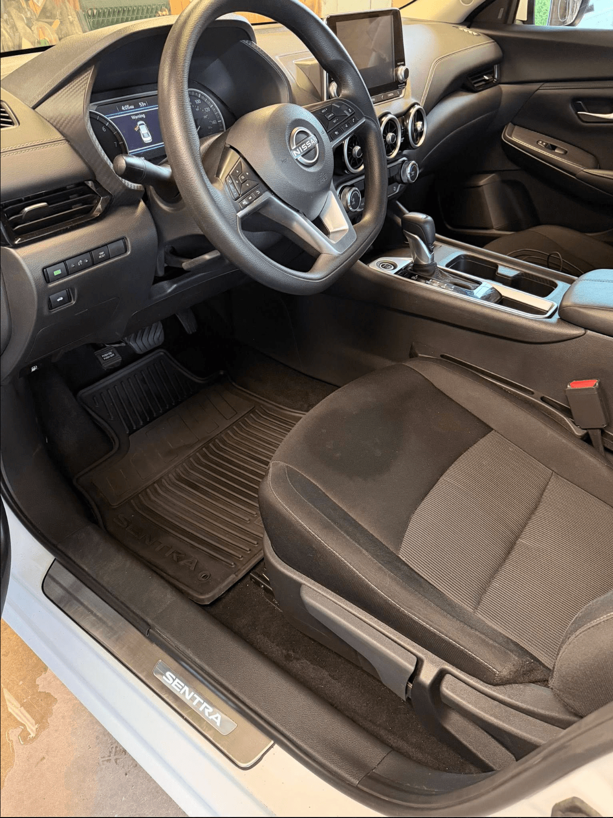 Nissan Sentra driver-side floor cleaned, fabric seat vacuumed, door sill wiped down after interior detail